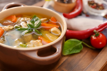 Casserole with delicious turkey soup on wooden board