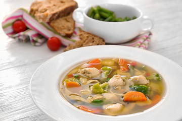 Plate with delicious turkey soup on wooden background