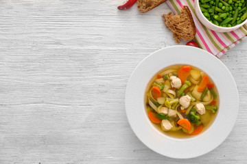 Plate with delicious turkey soup on wooden background