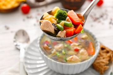 Ladle with turkey soup over bowl, close up