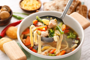 Ladle with turkey soup over saucepan, close up