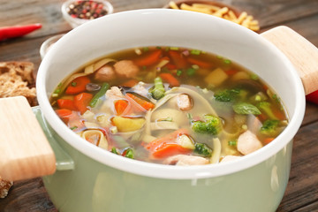 Saucepan with delicious turkey soup on table, close up
