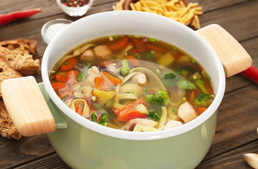 Saucepan with delicious turkey soup on table