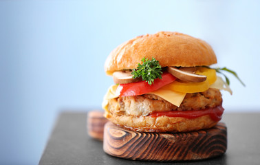Tasty turkey burger on wooden board, close up