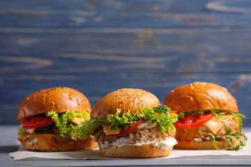 Composition of three tasty turkey burgers on color background