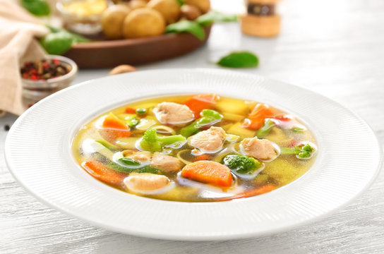 Plate with delicious turkey soup on wooden background, close up
