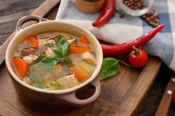 Casserole with delicious turkey soup on wooden board
