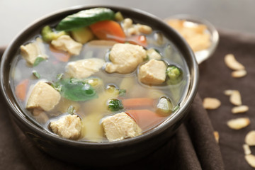 Bowl with delicious turkey soup on napkin, close up
