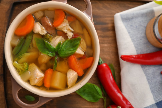Casserole with delicious turkey soup on wooden board