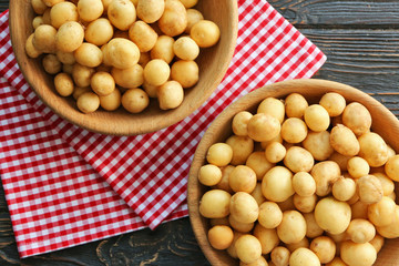Bowls with raw organic potato on wooden table