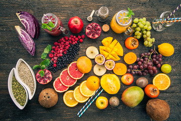 Fruits and frozen berries on dark rustic wooden table. Purple and yellow smoothie bowl formula. Clean eating concept. Various green and red veggies, fruit and superfoods ready to prepare smoothie bowl
