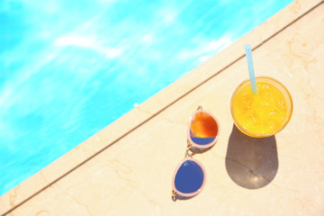 Tasty refreshing cocktail with sunglasses on edge of swimming pool © Africa Studio