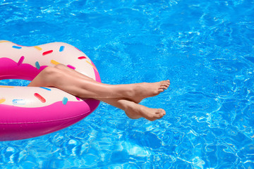Young woman relaxing on inflatable donut in swimming pool