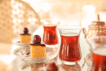 Turkish tea in traditional glasses with desserts on table