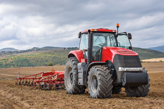 Farmer in tractor preparing farmland for seedbed.