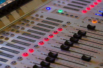 The buttons, sliders, lights, buttons and controls of a sound engineer or DJ's mixing desk or...