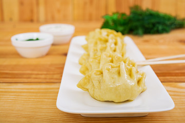 Delicious manti dumplings on wooden background