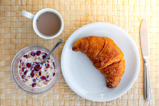 Fr&uuml;hst&uuml;ck mit M&uuml;sli und Croissant am Morgen, Draufsicht und Mogensonne