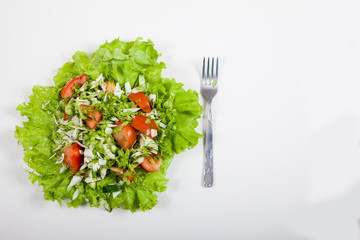 Salad of cucumbers, tomatoes and cabbage and fork on a white background