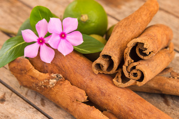 Cinnamon sticks on a wood table with flowers and green lemons in Martinique