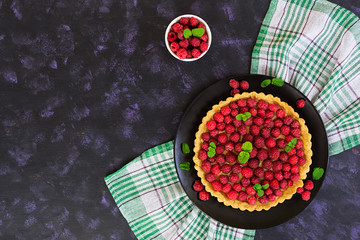 Delicious tart with custard and raspberry on wooden background