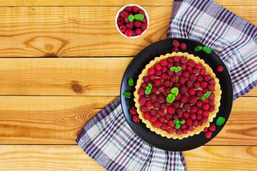 Delicious tart with custard and raspberry on wooden background