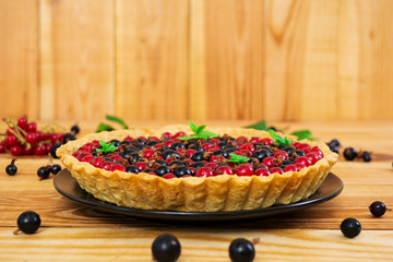 Delicious tart with custard and currant on wooden background