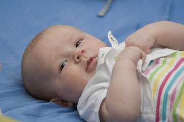Baby liegt auf dem Rücken und lächelt in die Kamera