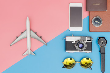 Toy plane with travel objects on the on blue and pink pastel background