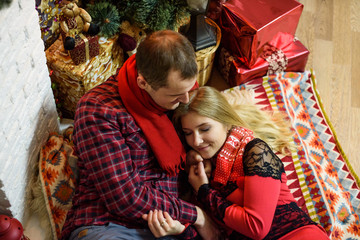 Obraz premium Young couple cuddling and kissing near christmas tree. Merry Christmas and Happy New Year!
