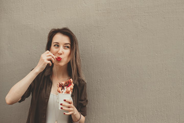Young woman eating bubble waffle with fruits, chocolate and marshmallow, with copy space