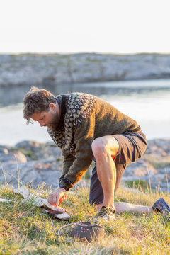 A man cooks cod on a camp fire on the Lofoten islands, Norway