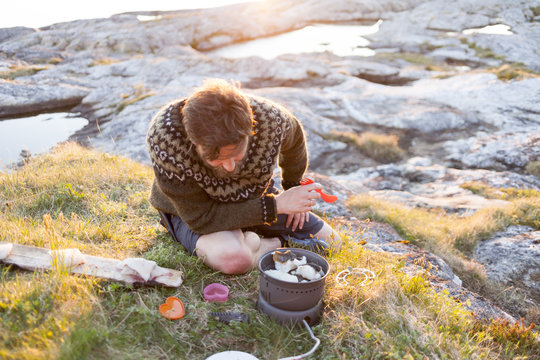 A man cooks cod on a camp fire on the Lofoten islands, Norway