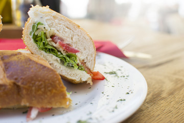 Delicious sandwiches with ham, tomato, cheese, and lettuce. Beautiful and tasty meal at the restaurant on a sunny day.