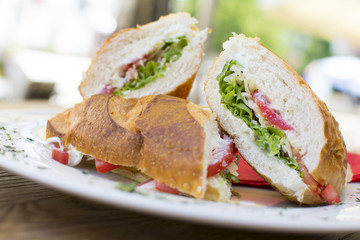 Delicious sandwiches with ham, tomato, cheese, and lettuce. Beautiful and tasty meal at the restaurant on a sunny day.