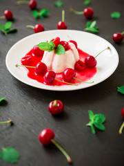 Tasty Italian jelly with cherry berries in white plate on dark table