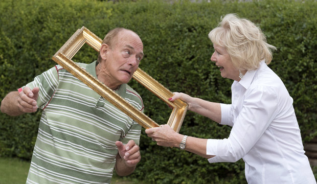 Elderly couple playing with a gold picture frame