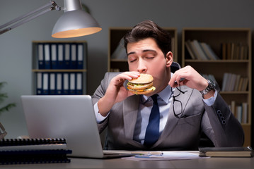 Businessman late at night eating a burger