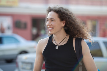 handsome man smiling on the street. Long curly hair man.