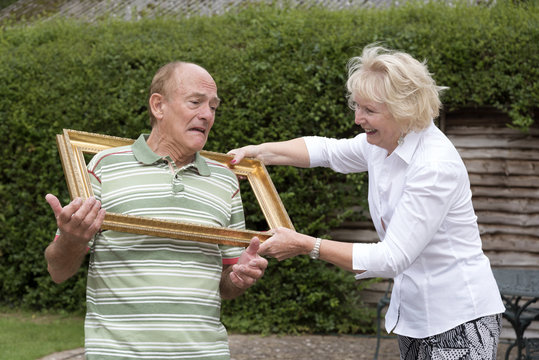 Elderly couple playing with a gold picture frame