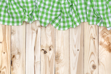 Green checkered tablecloth on wooden table, top view