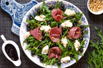 Salad with prosciutto arugula soft cheese cedar nuts and black currant