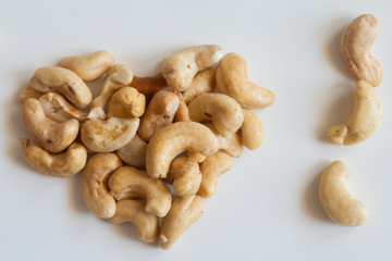 Heart shaped bunch of cashew nuts on white background