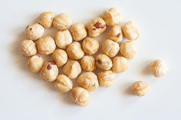 Heart shaped bunch of roasted hazelnuts on white background