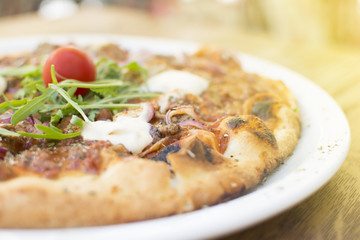 Hot pizza with melting cheese on a rustic wooden table. Delicious meal in the restaurant on a sunny day.