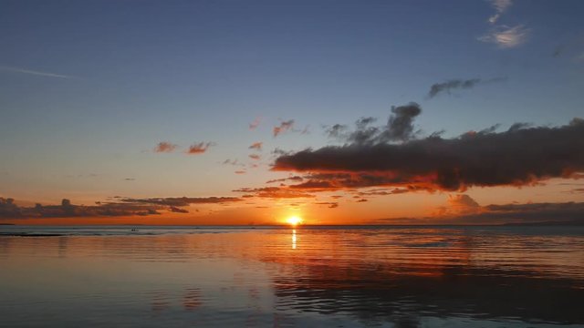 A colorful sunrise video from Dumaguete City shores with calm ocean. Sun is half way above the horizon. Presented in real time.