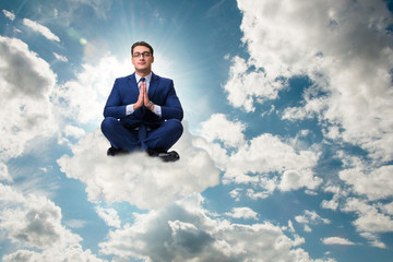 Businessman meditating in the sky