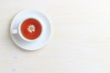 Tea in a white krushke on a saucer with chamomile and place under the text