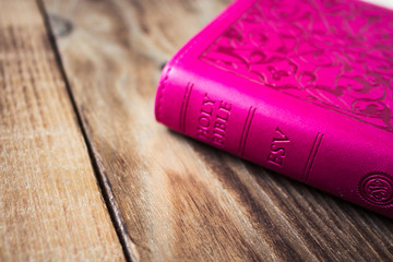 pink closed bible on wooden background