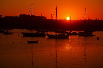 A spectacular sunset shot with silhouetted boats at the beach of Tavira, Algarve, Portugal